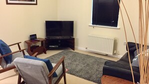 A living room with a TV, two sofas, a coffee table, and a small wooden side table. - Modern 2 Bed Apartment in Southampton (Southampton)