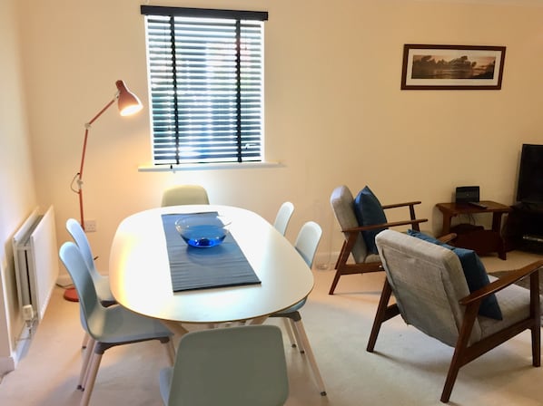 A dining area with a round table, chairs, a bowl, and a lamp.