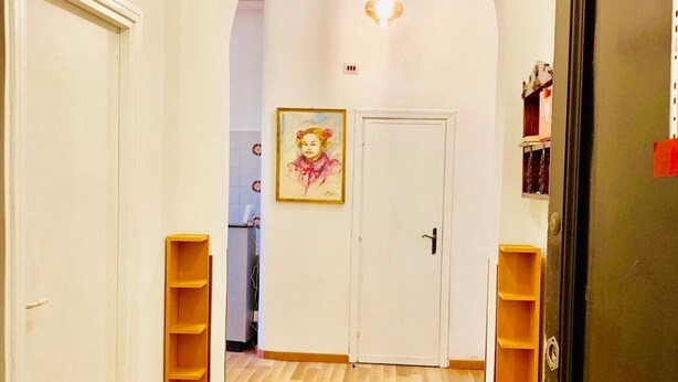 A hallway with wooden flooring, white walls, and an arched doorway leading to another room. - Comfort Inn Roma Termini (Rome)