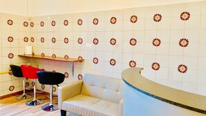 A room with a white sofa, two bar stools, a wooden shelf, and a curved reception desk. - Comfort Inn Roma Termini (Rome)