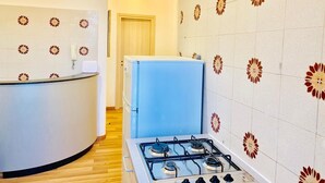 A compact kitchen with a gas stove, a blue refrigerator, and patterned tiles. - Comfort Inn Roma Termini (Rome)
