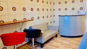 A room with a sofa, a red chair, a blue bar counter, and a patterned wall. - Comfort Inn Roma Termini (Rome)