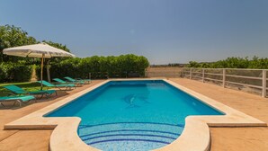 A rectangular swimming pool with a dolphin logo, surrounded by a tiled deck and green lounge chairs. - Villa with detached house, air conditioning, wifi, garden, private swimming pool (Santa Margalida)