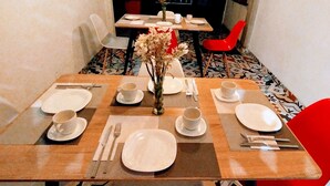 A dining table set with plates, cups, and cutlery, a vase with dried flowers, and a red chair. - Casa SAB  Los Andes (Bogotá)