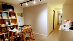 A cozy living space with a wooden table, a bookshelf, and a TV mounted on the wall. - Casa SAB  Los Andes (Bogotá)