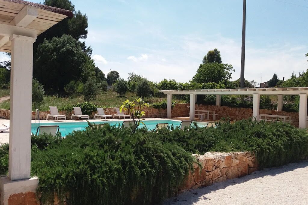 A pool area with lounge chairs and a pergola.