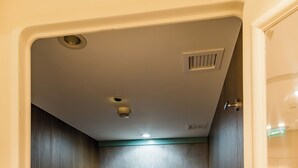 A compact room with a single bed, a small bedside table, and a wall-mounted light fixture. - Sleepover Terminal 1, Concourse D – formerly sleep ‘n fly (Dubai)