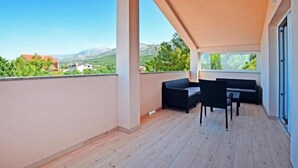 A balcony with a wooden floor, a black sofa, and a table.