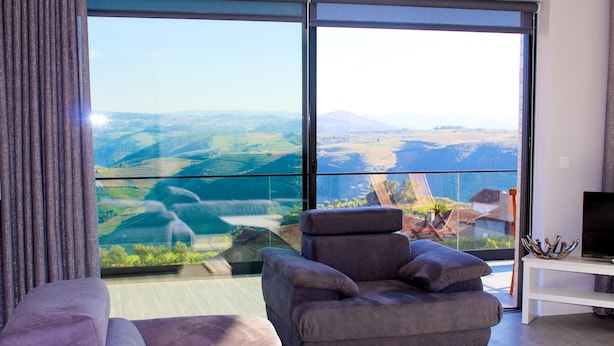 Una sala de estar moderna con un amplio ventanal que ofrece una vista panorámica de un valle y montañas.