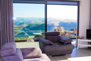 A modern living room with a large window offering a scenic view of a valley and mountains. - Galafura Design House (Peso da Régua)