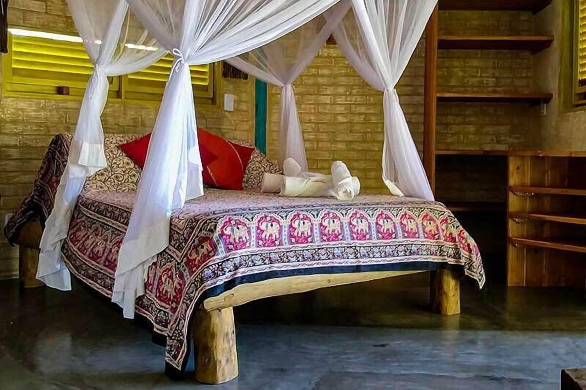 Un lit à baldaquin, une couvre-lit à motifs et un mur de briques en arrière-plan.