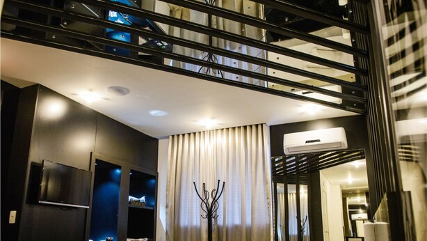 Une chambre d’hôtel moderne équipée d’un lit, d’une télévision, d’un minibar et d’un balcon avec une rambarde.