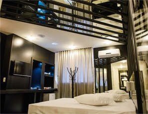 Une chambre d’hôtel moderne équipée d’un lit, d’une télévision, d’un minibar et d’un balcon avec une rambarde.