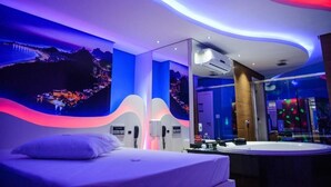 Une chambre d’hôtel moderne, équipée d’un lit, d’un grand miroir, d’une salle de bain avec baignoire et offrant une vue sur la ville.