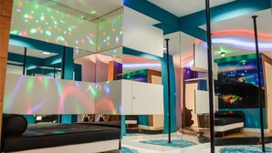 Une chambre d’hôtel moderne avec un grand lit, un mur entièrement recouvert de miroirs et un luminaire au plafond.