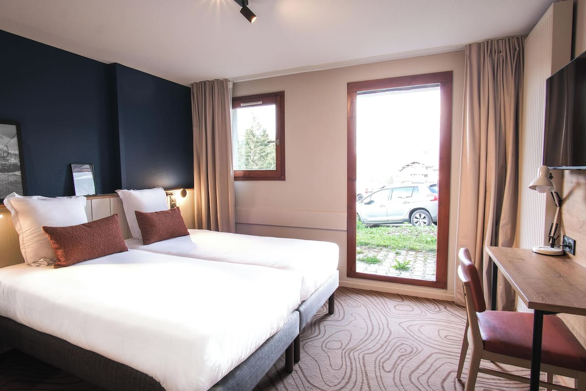 Ein Hotelzimmer mit Bett, Schreibtisch, Stuhl, Fernseher und einem Fenster mit Ausblick.
