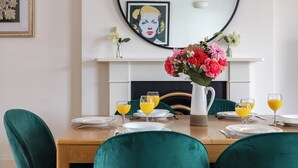 A dining table set for four with green chairs, a vase of flowers, and glasses of orange juice. - 3-bedroom apartment Lancaster gate (London)