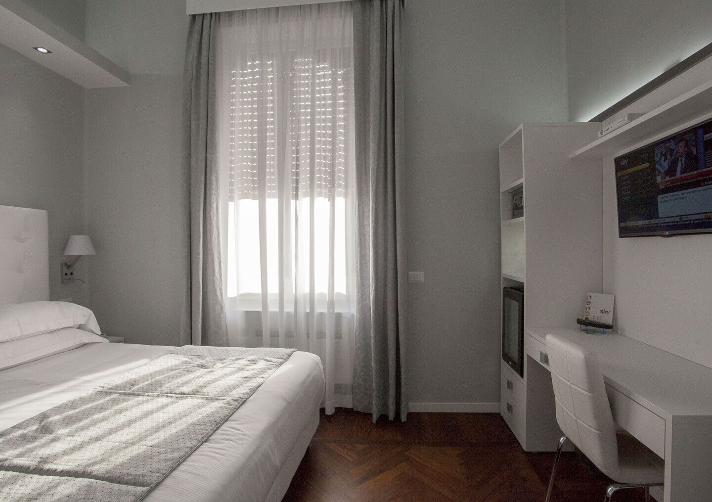 A modern hotel room with a large bed, a desk, and a television.