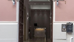 Una entrada con un arco blanco, una mesa de recepción y un buzón.