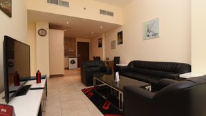 A modern living room with a black leather sofa, a flat-screen TV, and a dining area with a table and chairs.