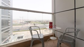 A balcony with two metal chairs, a small table, and a red object on the wall.