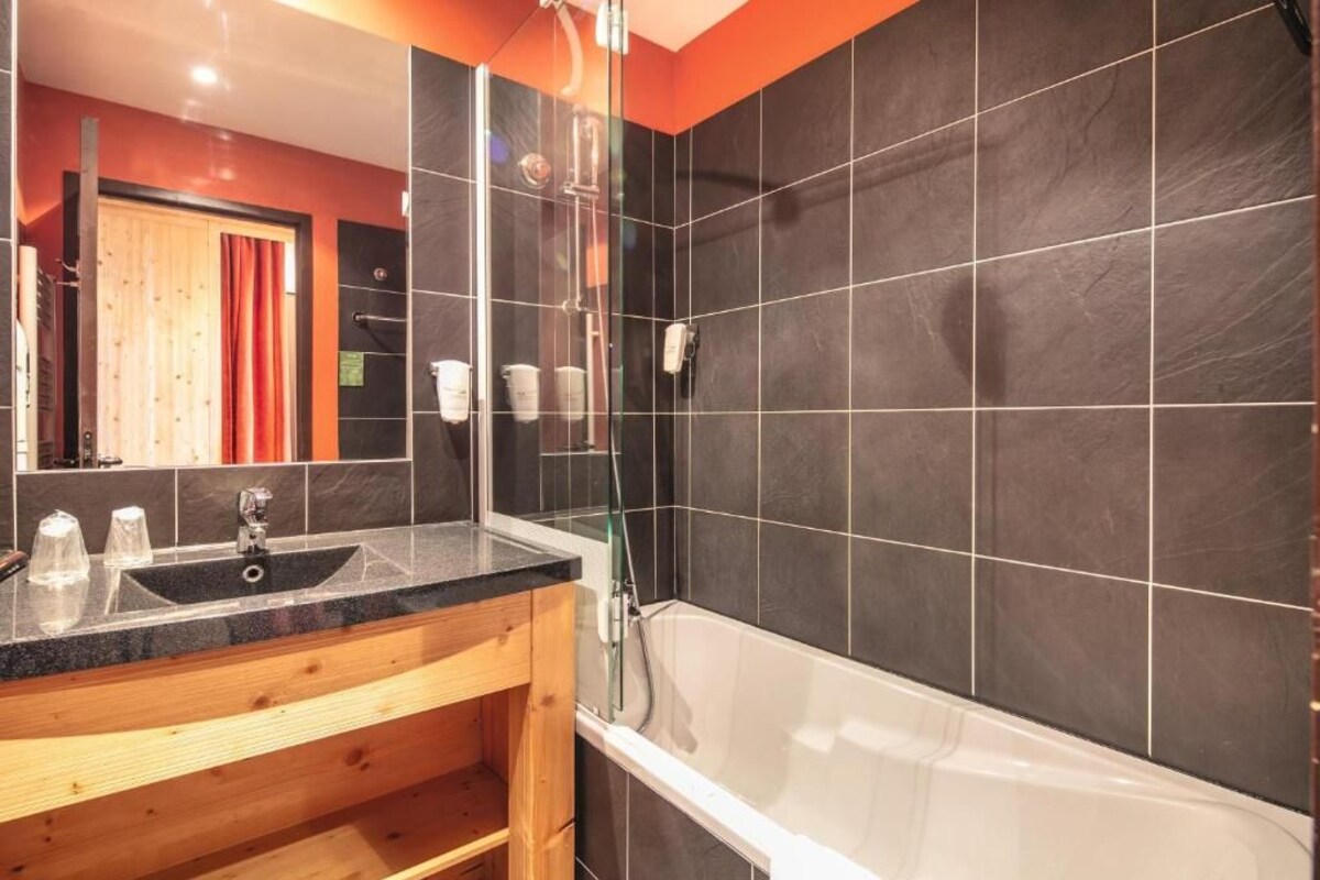 A bathroom with a glass-enclosed shower, a sink, and a bathtub.