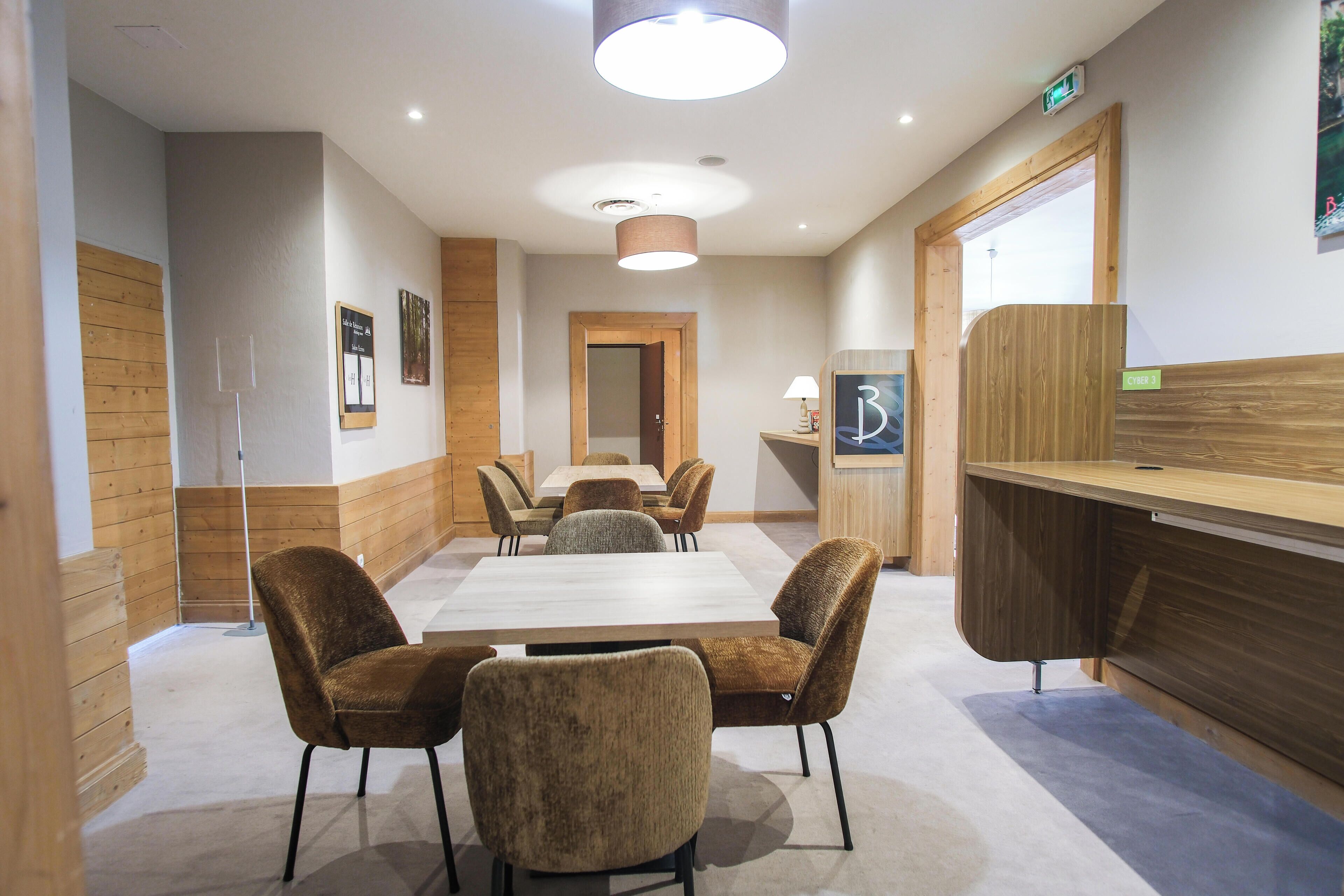 A conference room with a long table, four chairs, a wooden reception desk, and a door leading to another room.