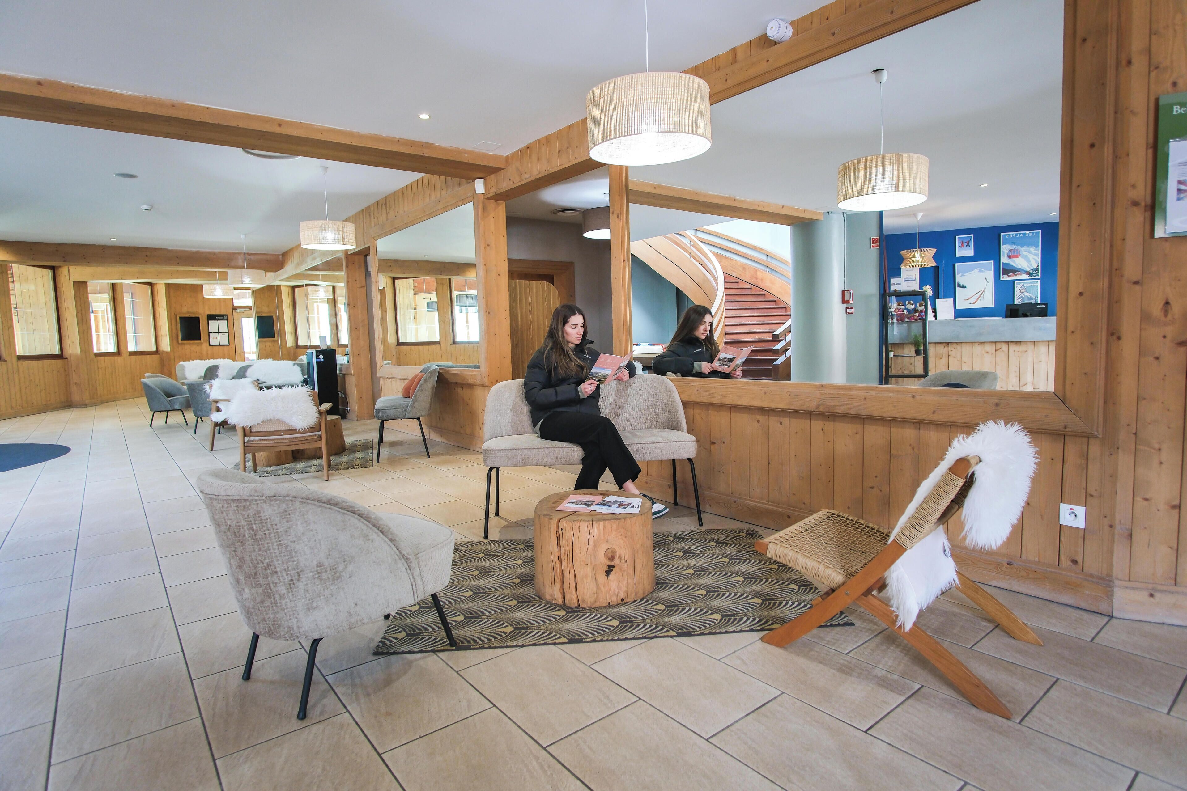 A hotel lobby with wooden walls, a reception desk, and seating areas.