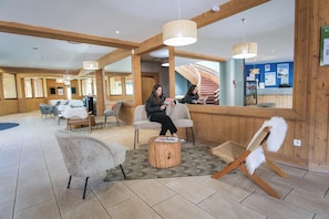 Un hall d’hôtel avec des murs en bois, un comptoir d’accueil et des espaces aménagés avec des sièges.