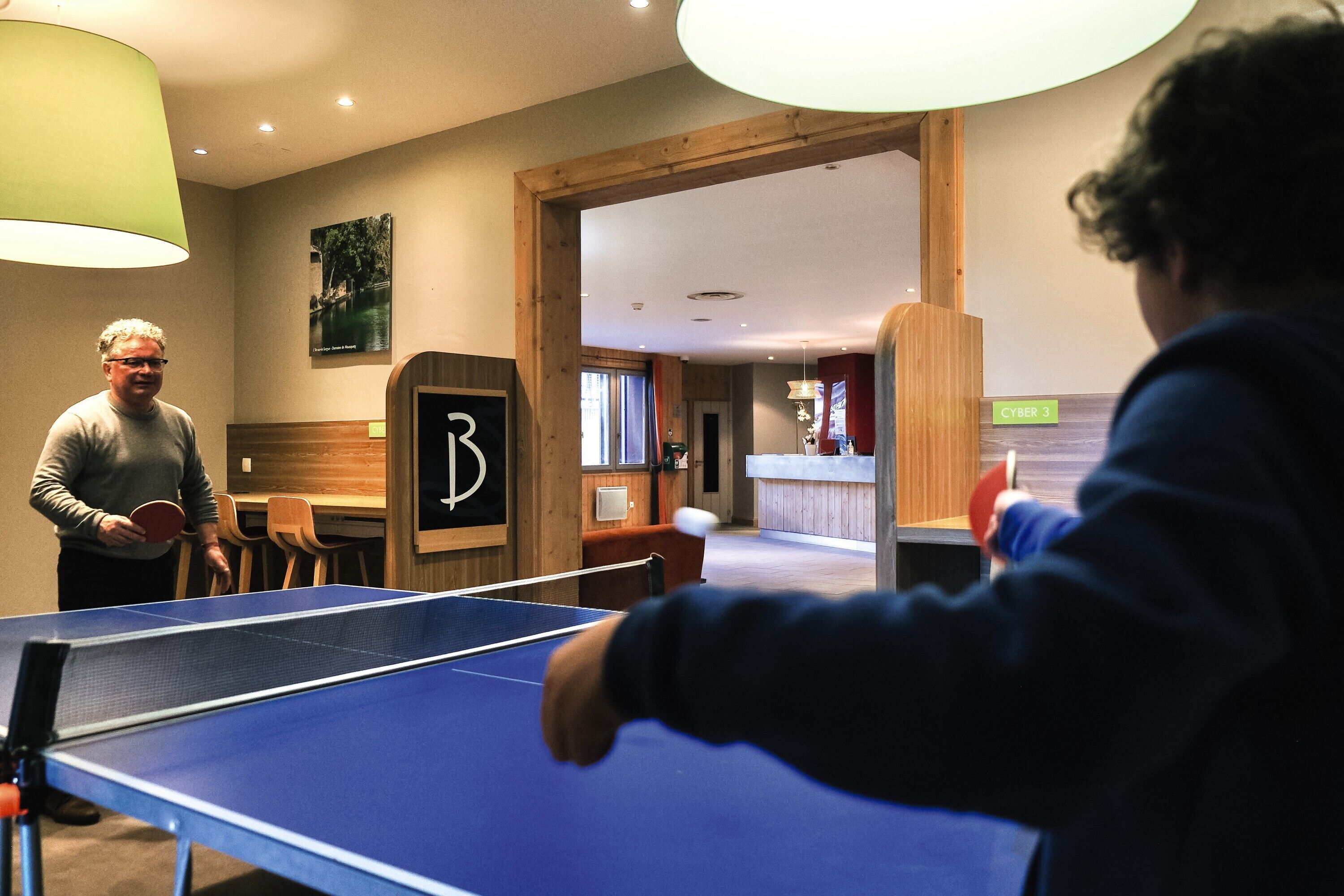A ping pong table in a room with wooden walls and a green lamp.