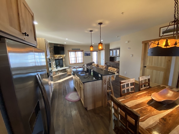 A spacious kitchen with a central island, wooden cabinets, and a stone fireplace.