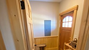 A narrow hallway with a wooden door, a small bench, and a tiled floor.