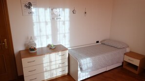 Un dormitorio con cama, cómoda, mesita de noche y adornos en la pared.