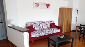 Un salón con sofá, una mesita, un armario y un adorno de pared.