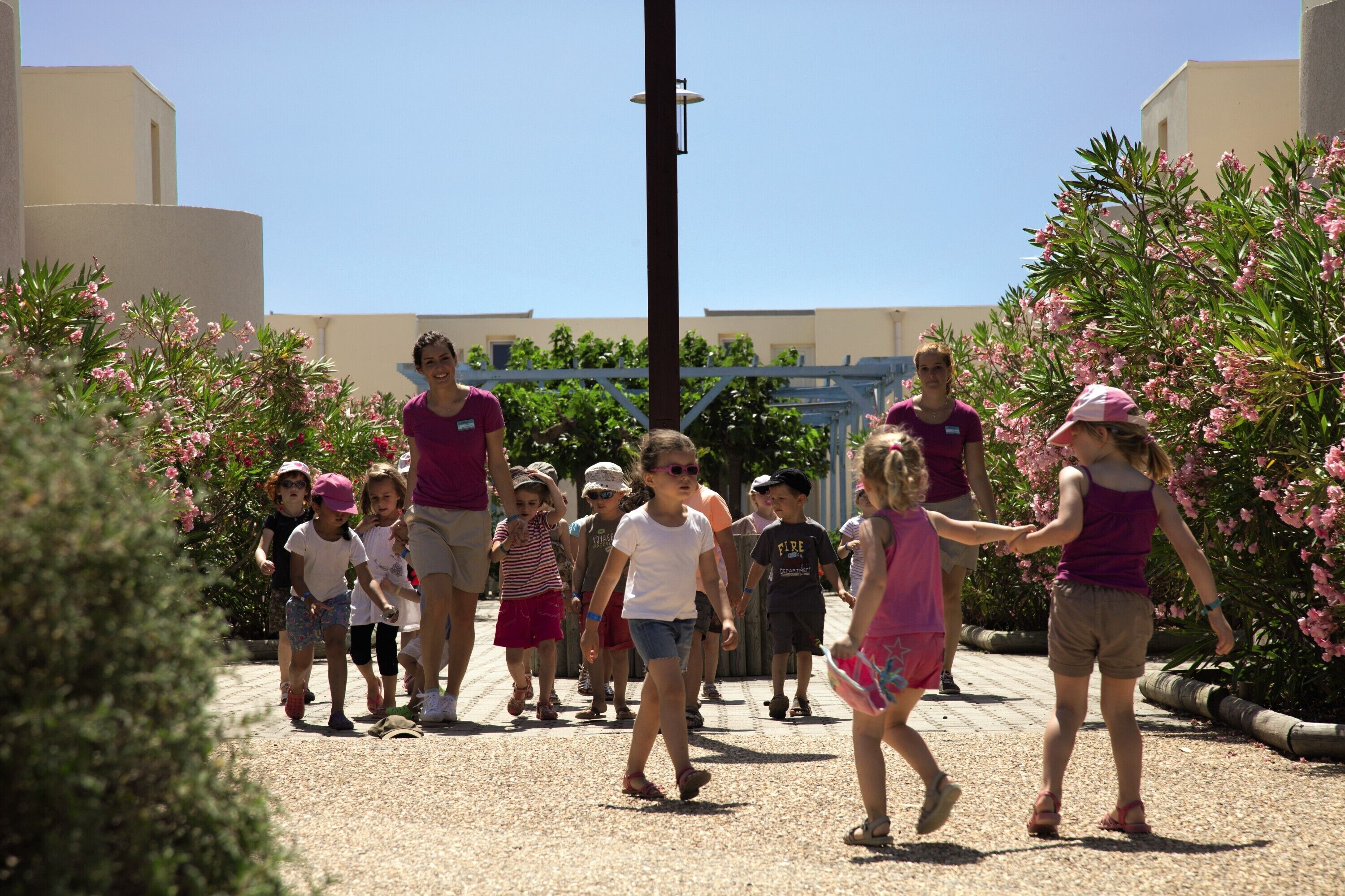 A group of people walking on a pathway surrounded by greenery and buildings.