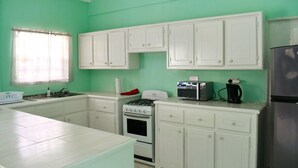A kitchen with white cabinets, a gas stove, a microwave, and a refrigerator.