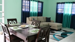 A dining area with a table set for two, a sofa, and curtains.