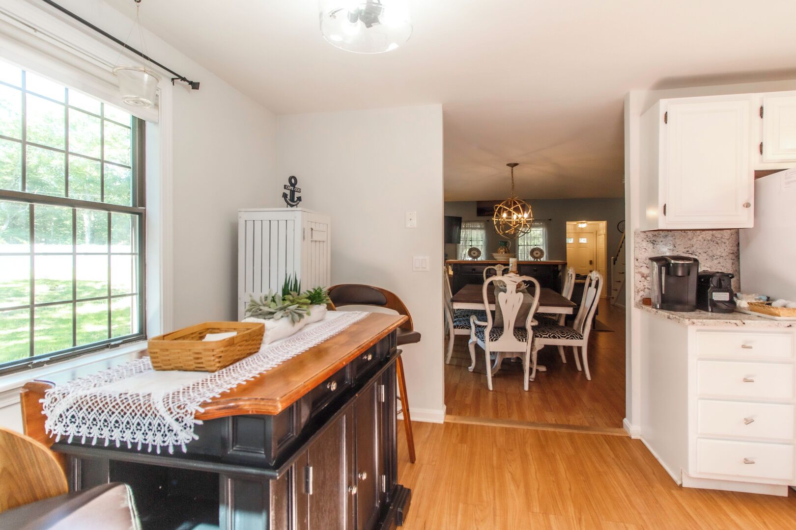 A kitchen with a wooden island, white cabinets, and a dining area with a chandelier.