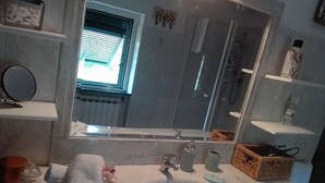 A bathroom with a white sink, a mirror, and a window with blinds. There are towels, a soap dish, and a bottle on the counter.