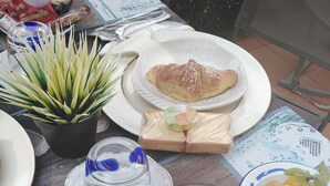 A table set with various food items, including bread, pastries, and a bowl of fruit.