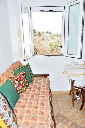 Une pièce avec un lit, une fenêtre, une table avec un téléphone et une chaise.