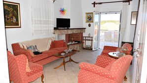 Un salon comprenant un canapé, des fauteuils, une table basse, un téléviseur à écran plat et une cheminée.