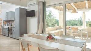 A modern kitchen with grey cabinets, a flat-screen TV, and a dining area with a white table and chairs. - Dimora il Mandorlo -The Plum tree private jacuzzi (Ostuni)