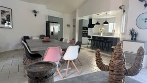Eine moderne Küche mit einer zentralen Kochinsel, schwarzen Stühlen und einem Esstisch mit pinkfarbenen Stühlen.