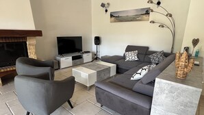 Ein modernes Wohnzimmer mit grauem Sofa, Flachbildfernseher, Couchtisch und Kamin.