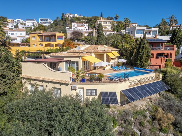 Eine Villa im mediterranen Stil mit Swimmingpool, Solaranlage und Terrasse mit Liegestühlen.