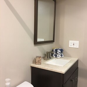 A bathroom with a white sink, dark cabinetry, a mirror, and a towel rack with towels.