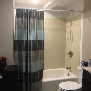 A bathroom with a bathtub, toilet, and shower curtain.