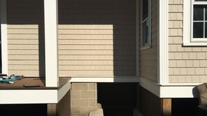 Ein Teil eines Hauses mit einem kleinen, abgeschlossenen Wintergarten, einem Fenster und einer Tür, die zu einem Keller führt.