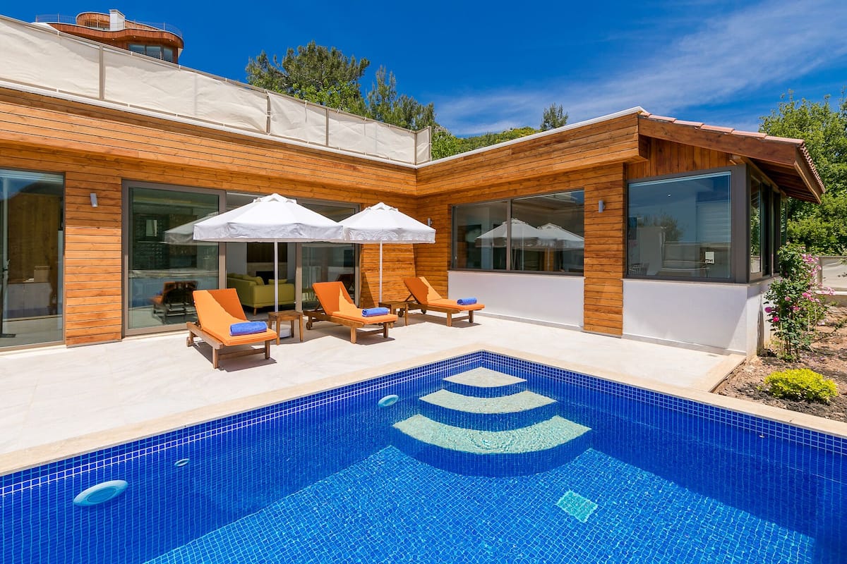 A modern house with a swimming pool, wooden exterior, and glass doors.
